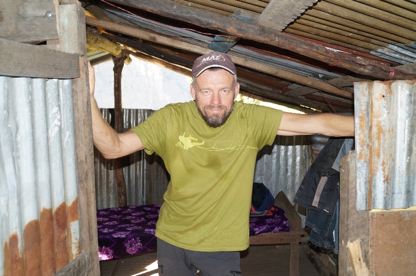 Bilde av Geir Kipenes som står inne i et skur av bølgeblikk og treverk.